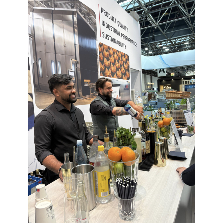 Zwei Barkeeper von Easy Bar and Eventservice mixen Drinks an einer mobilen Bar während einer Messeveranstaltung