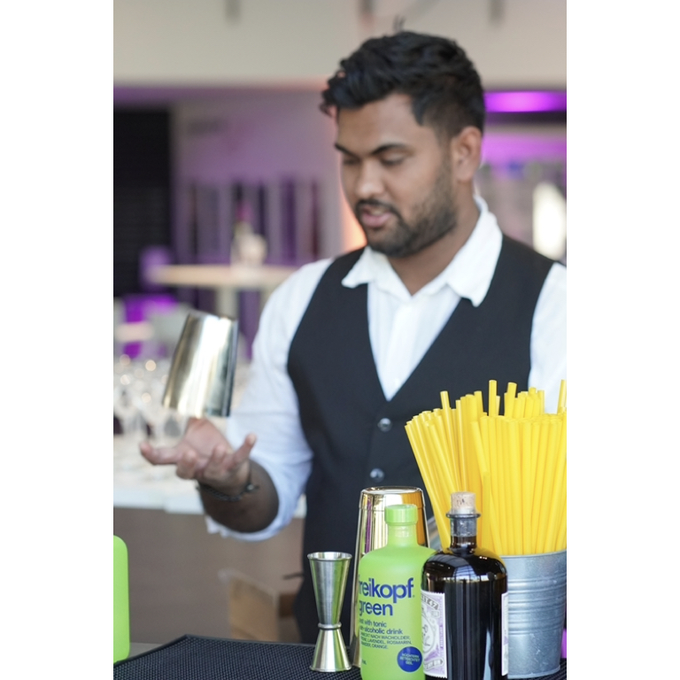 Barkeeper mit Cocktailshaker hinter der Bar im Einsatz