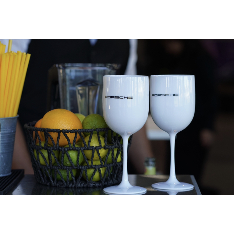 Weiße Cocktailgläser mit Porsche-Logo neben Zitronen und Orangen an einer Eventbar