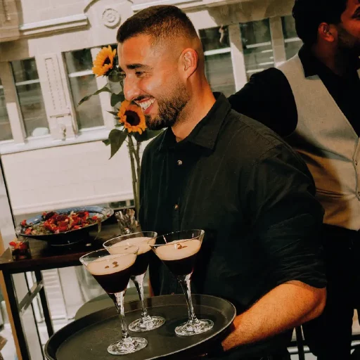 Easybarservice Kellner lächelnd mit einem Tablett mit Café Kreationen.